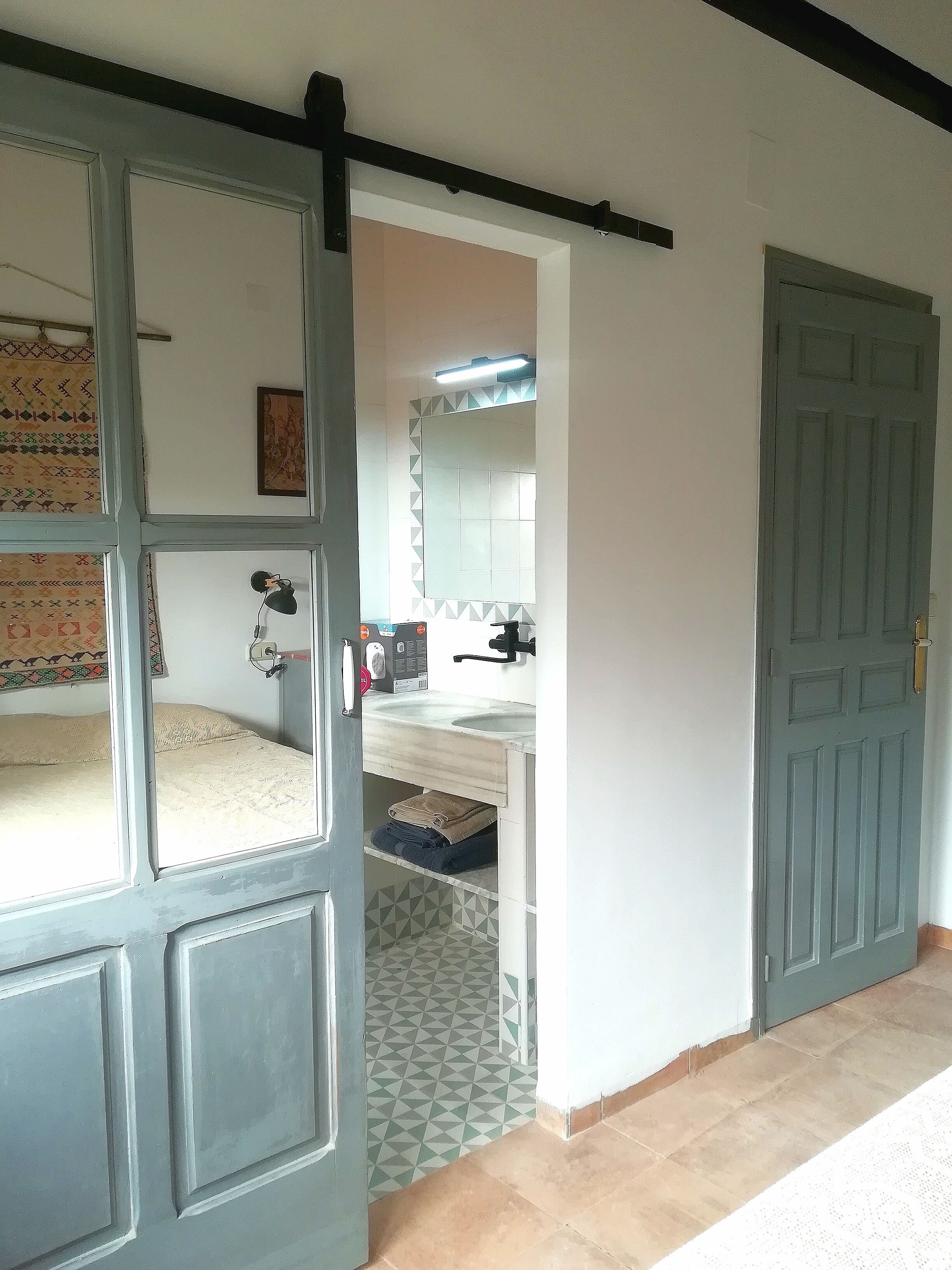 A room with a bed, a desk, a chair, a window, and a door.