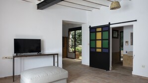 Un salon moderne doté d’un téléviseur à écran plat, d’un canapé et d’une porte coulissante aux panneaux colorés.