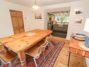 A spacious dining area with a wooden table and chairs, a patterned rug, and a view into the kitchen.