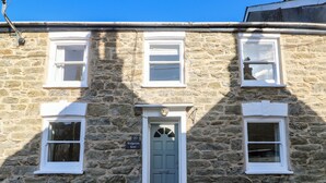 A stone building with a central door, two windows on each side, and a small sign above the door. - Widgeons Keel (Falmouth)