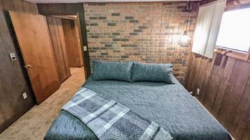 Un dormitorio con pared de ladrillo, una puerta de madera y una ventana con persianas.