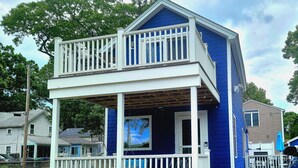 A two-story house with a balcony, a covered porch, and a front yard with flowers. - The Loft at Oakland Beach 
Ask About Off-season Discounts 
5 min from Airport. (Warwick)