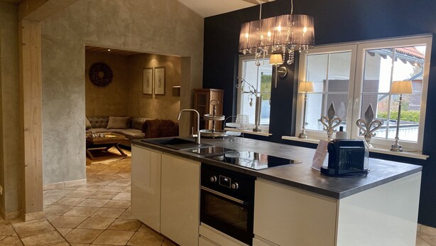 Een moderne keuken met een groot eiland, een ingebouwde oven en een zithoek met een bank en salontafel.