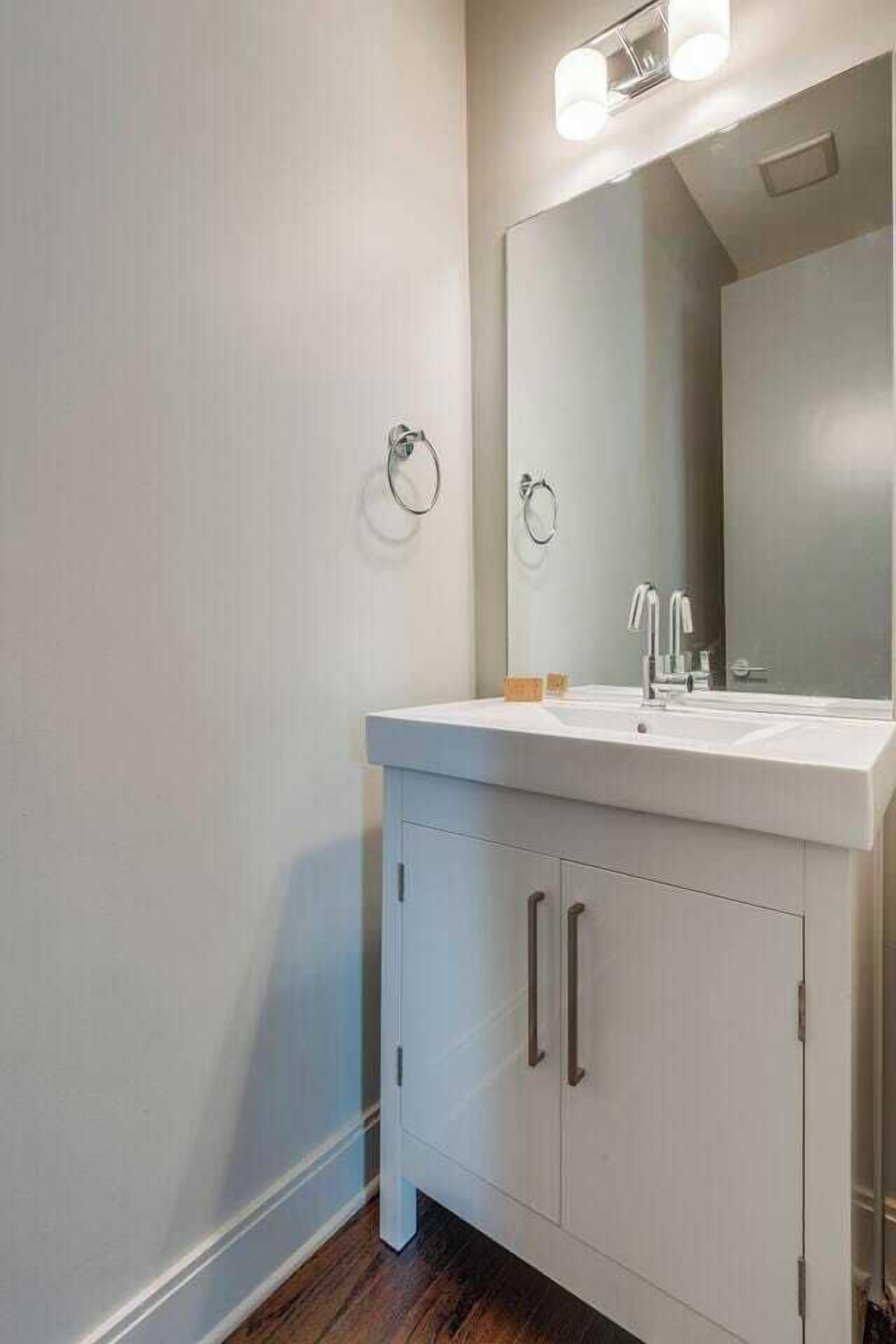 Ein modernes Badezimmer mit einem weißen Waschtisch, einem großen Spiegel und einem Handtuchring an der Wand.