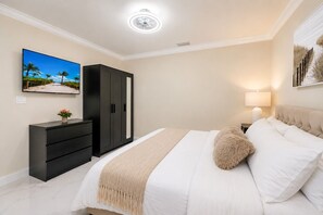 A bedroom with a bed, a dresser, a wardrobe, a TV, and a lamp.