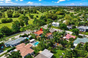 A residential area with houses, a swimming pool, and a golf course in the background.