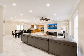 A modern living room with a sectional sofa, a dining area, and a kitchen in the background.