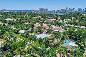 Un barrio residencial con casas, palmeras y vistas al océano y al horizonte urbano.