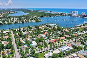 Vista aérea de un pueblo costero con un puerto deportivo, zonas residenciales y edificios a lo largo del paseo marítimo.