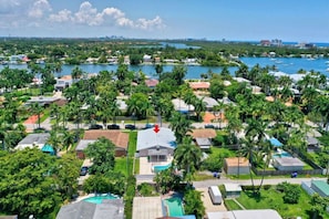 Vista aérea de una zona residencial costera con casas, palmeras y un puerto deportivo.