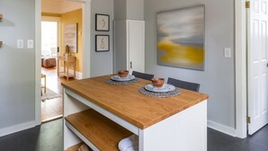 A dining area with a wooden table, two copper bowls, and a white cabinet. - Bright & Cozy Home | Walkable, Private Yard + WiFi (Seattle)