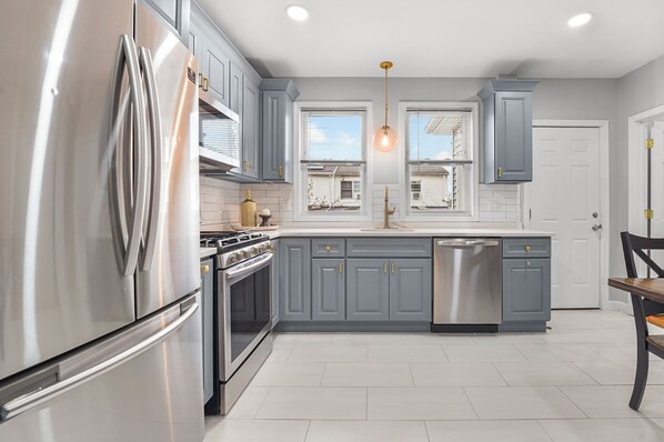 A modern kitchen with grey cabinets, stainless steel appliances, and a central island.