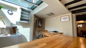 A modern kitchen with a wooden countertop, a stone accent wall, and a skylight.