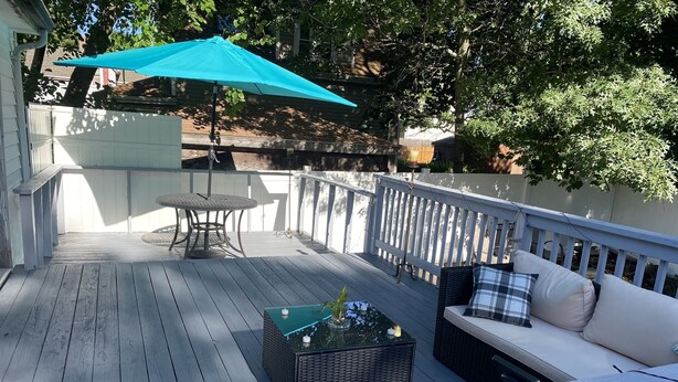 Eine Holzterrasse mit einem Tisch, Stühlen, einer Couch und einem kleinen Tisch mit einer Pflanze.
