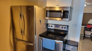 A compact kitchen with a stainless steel refrigerator, a microwave, and an oven. - Beautiful lake side cottage (Hampden)