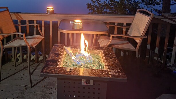 A deck with a fire feature, chairs, and a table. - Beautiful lake side cottage (Hampden)