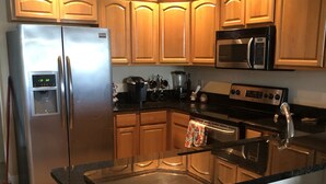 Una cocina con armarios de madera, electrodomésticos de acero inoxidable, un microondas, un refrigerador y una estufa.