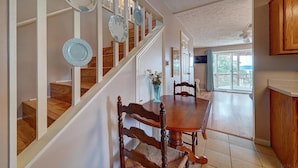 A staircase with hanging plates, a dining table with chairs, and a view of the outdoors.