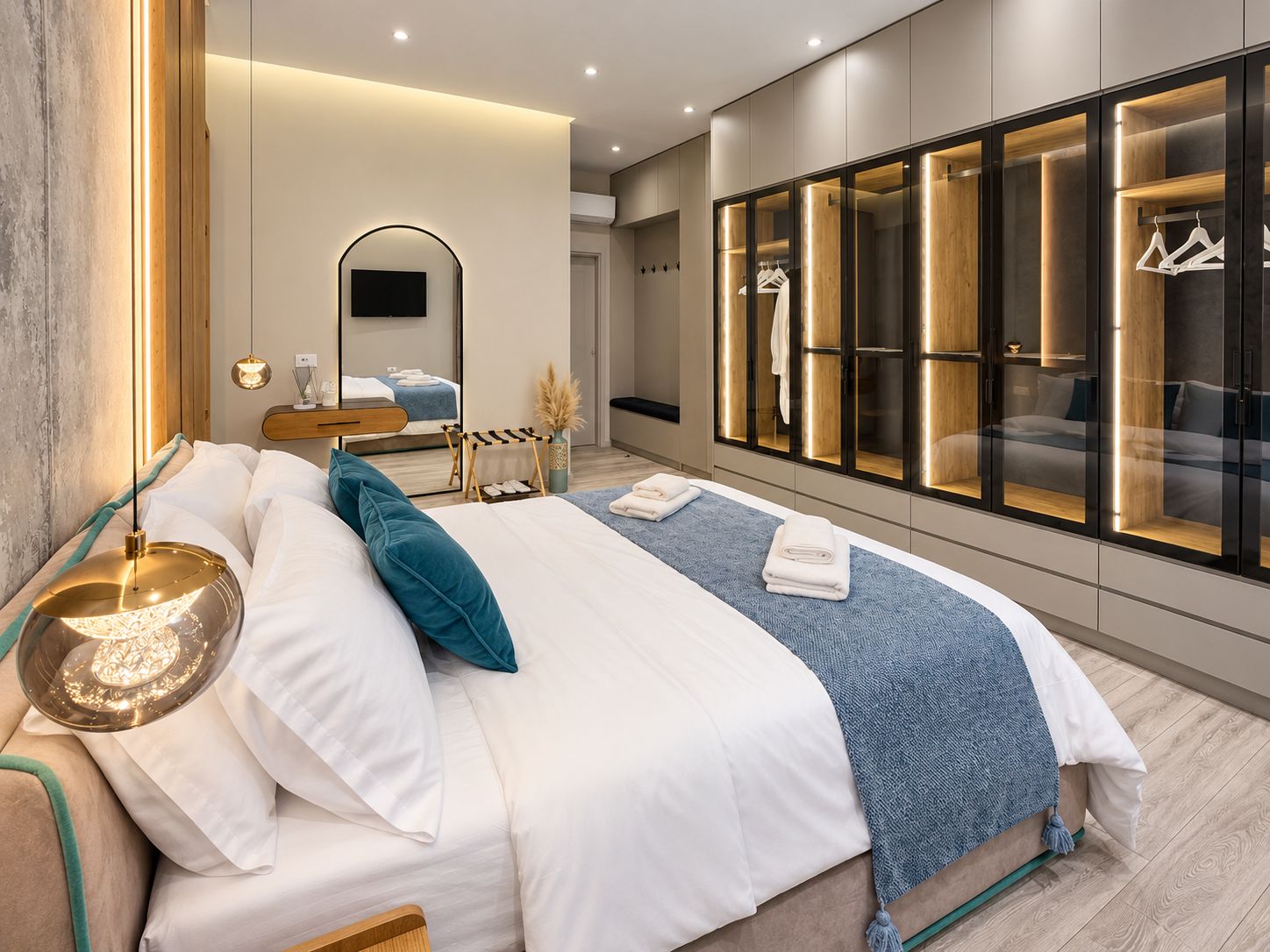 A modern bedroom with a large bed, bedside tables, a mirror, and a wardrobe with illuminated sections.