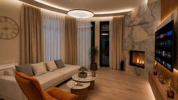 A modern living room with a sofa, armchair, coffee table, fireplace, and a wall-mounted TV.