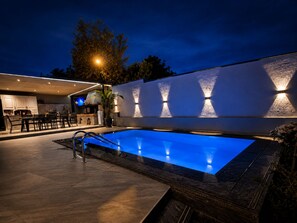 A swimming pool with a modern design, a bar area, and a well-lit outdoor space. - Joan Luxury Villa Apt with private pool & Gym (Tirana)