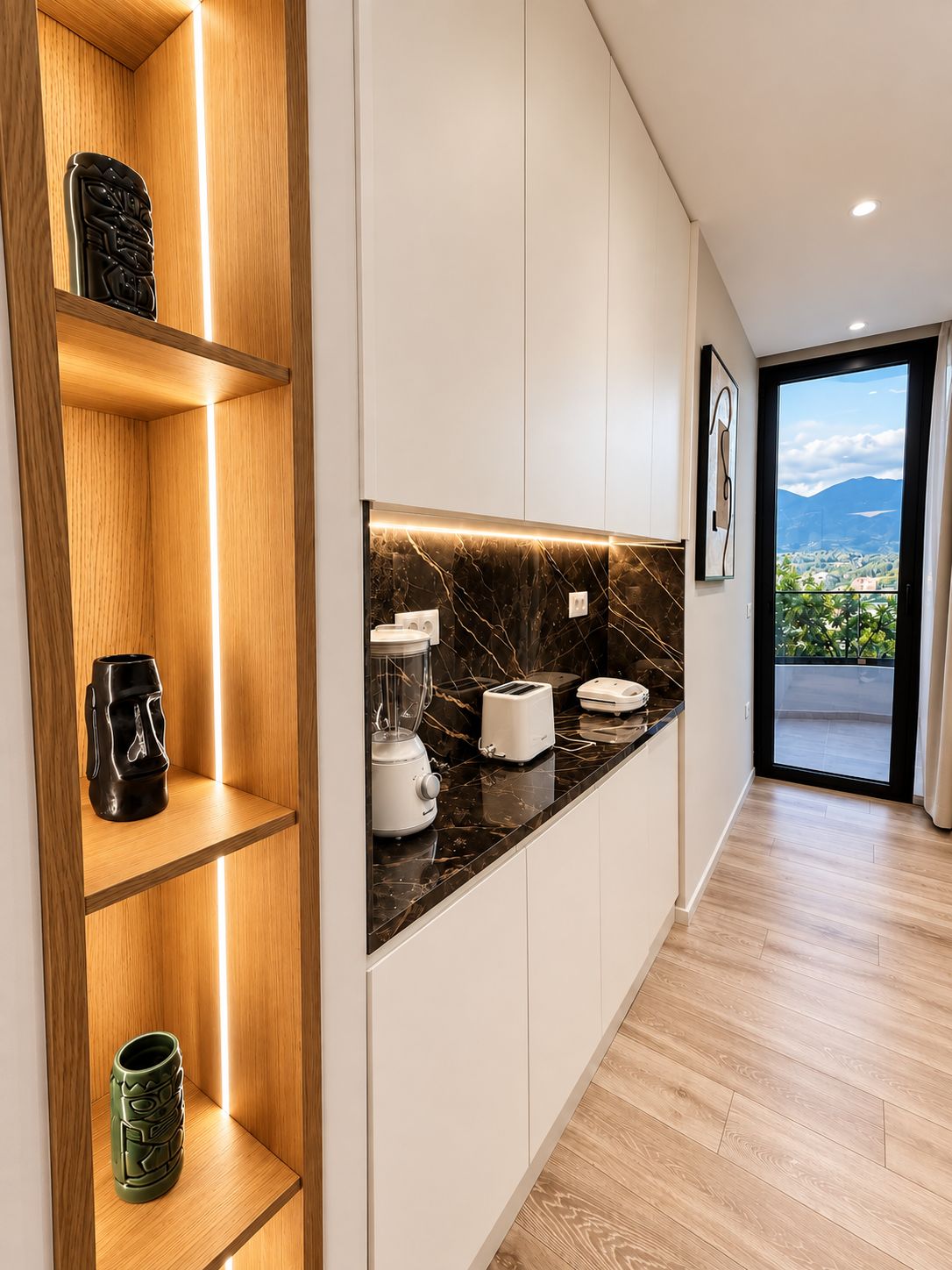 A modern kitchen with wooden shelves, a marble countertop, and a view of the outdoors.