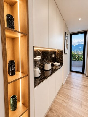 A modern kitchen with wooden shelves, a marble countertop, and a view of the outdoors. - Joan Luxury Villa Apt with private pool & Gym (Tirana)