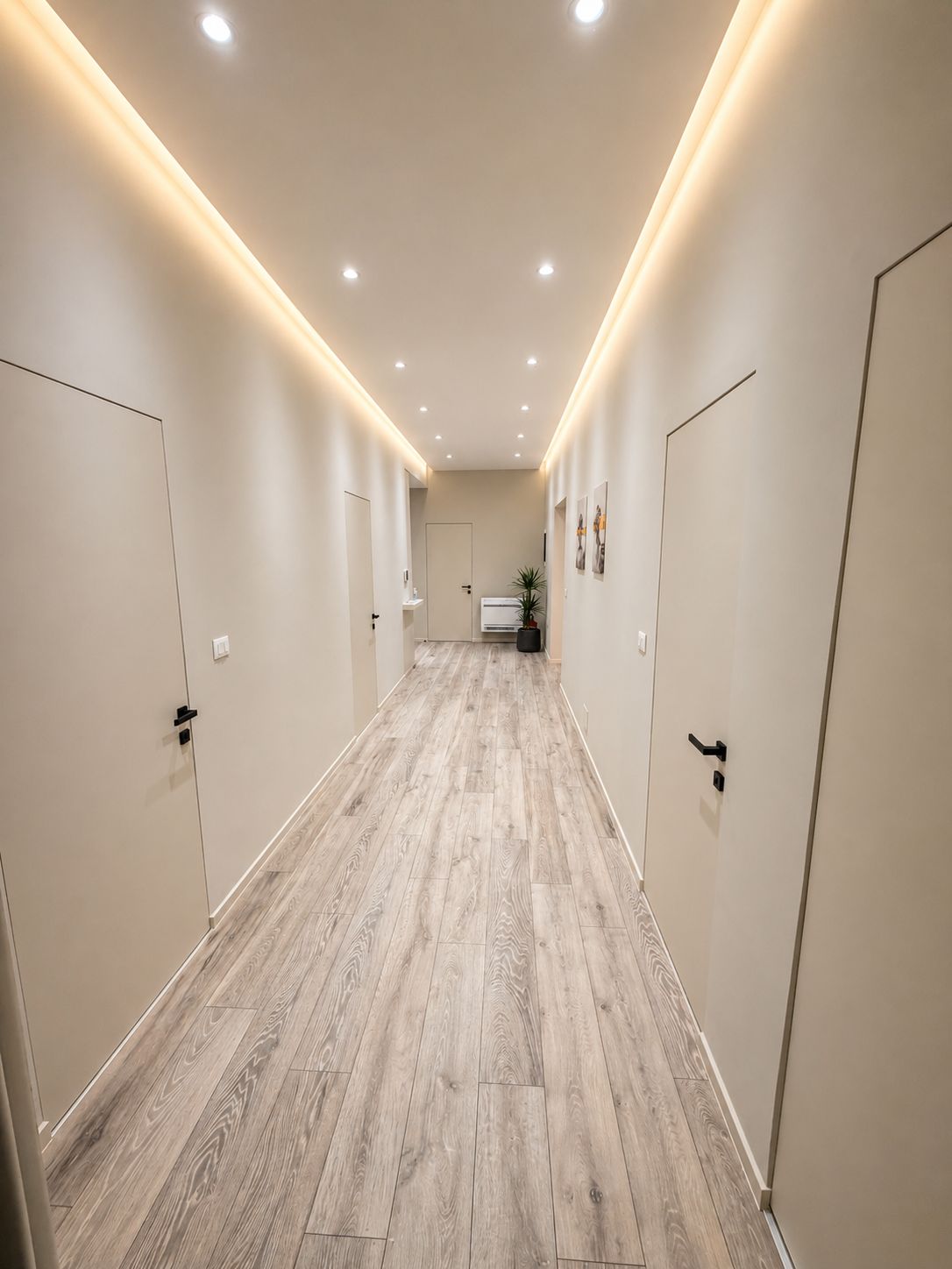 A hallway with wooden flooring, white walls, and doors on both sides.
