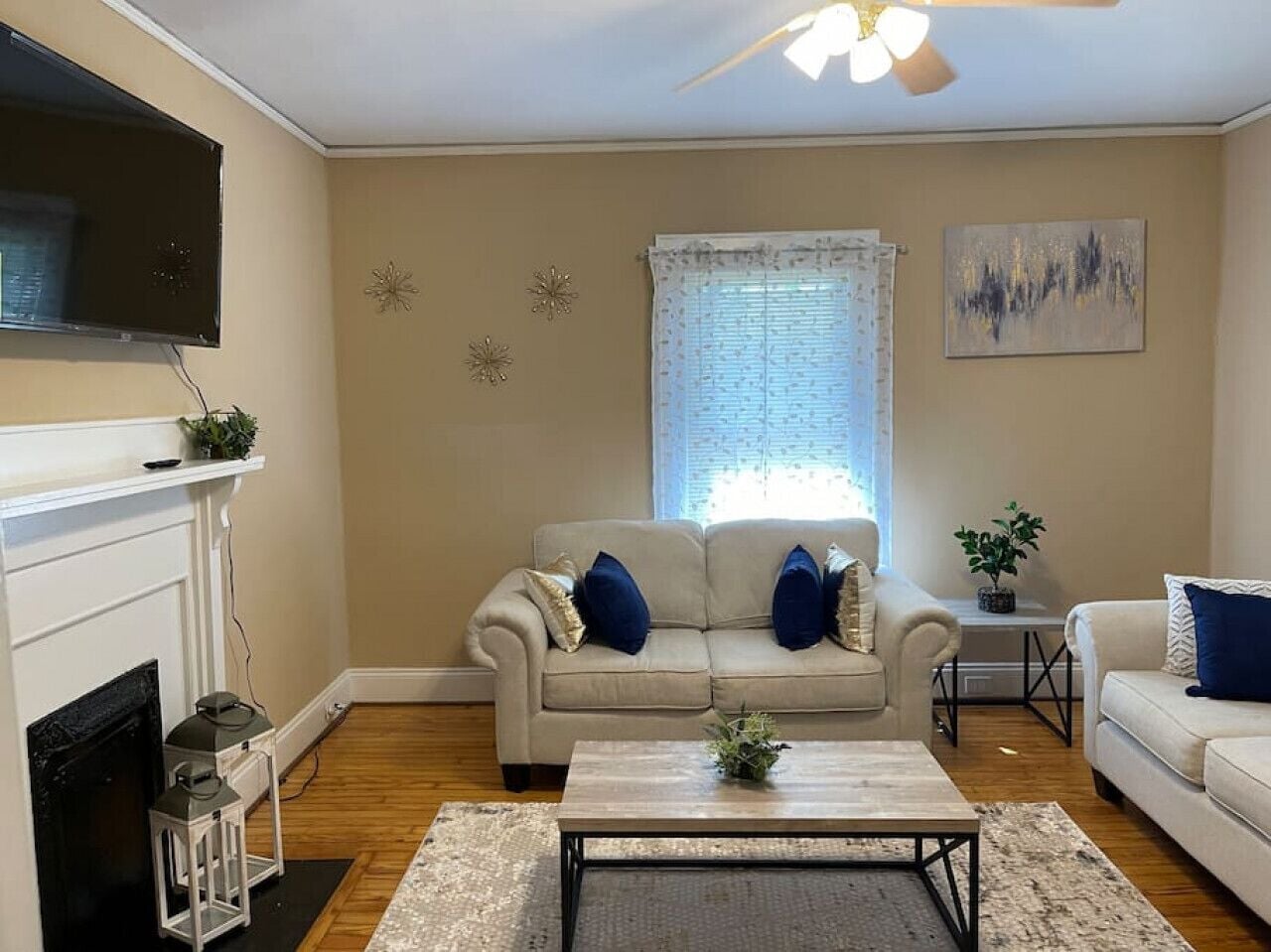 A living room with a fireplace, a beige sofa, a coffee table, and a television mounted on the wall.
