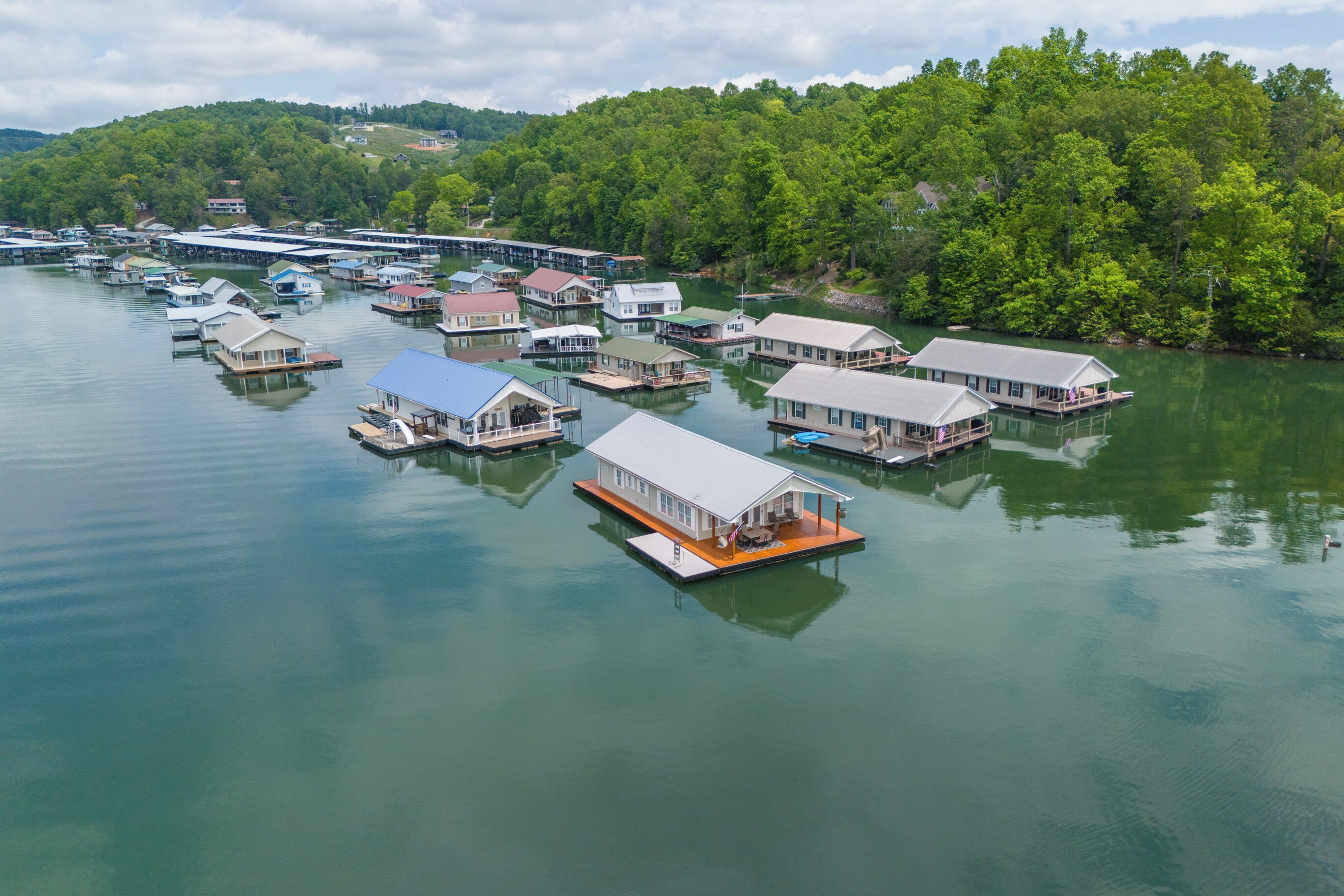 Un grupo de casas flotantes en un lago tranquilo, rodeadas de un bosque denso.