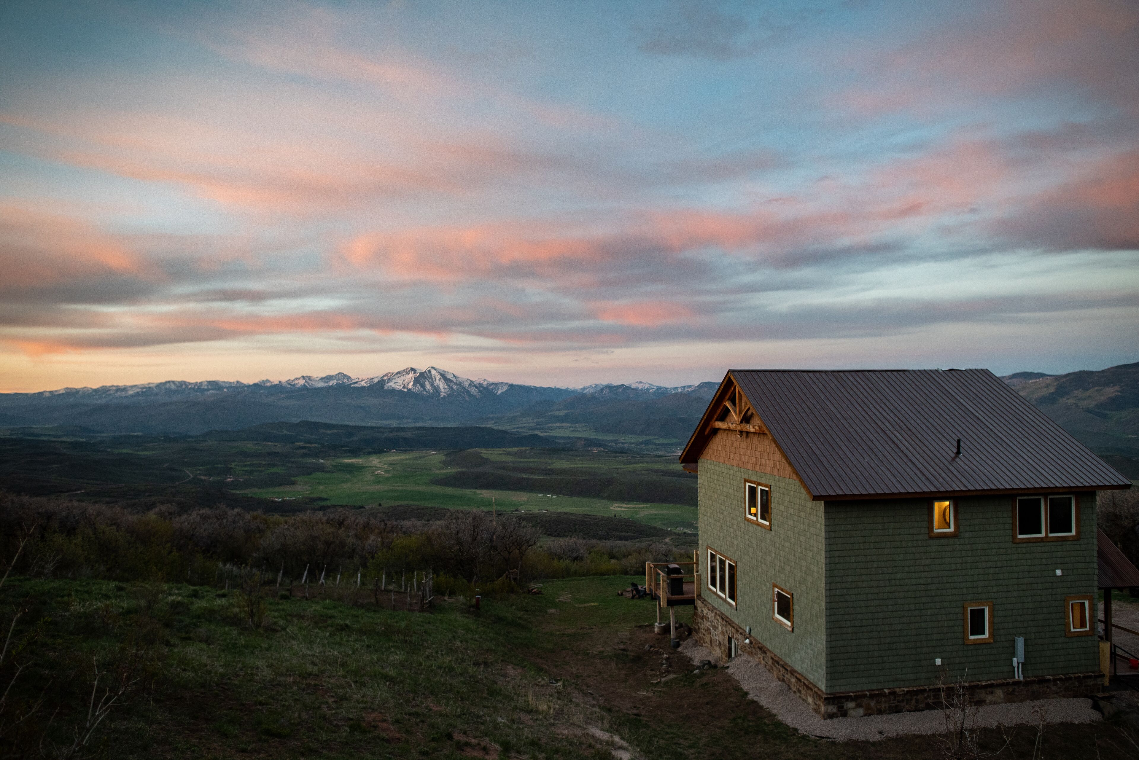 A house with a sloped roof, a porch, and a view of mountains in the background.