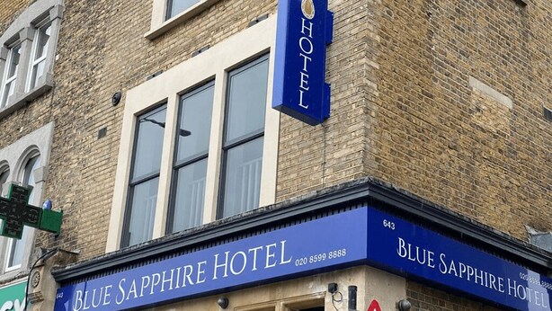 The exterior of the Blue Sapphire Hotel, featuring a prominent blue sign with the hotel's name and contact number. - Blue Sapphire Hotel (Ilford)