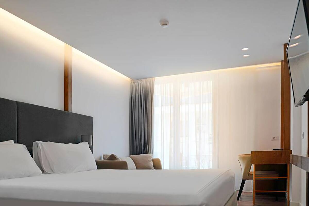 A modern hotel room with a large bed, a desk, and a television.