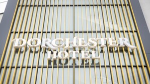 Letrero del Hotel Dorchester con líneas verticales amarillas y una fachada moderna.