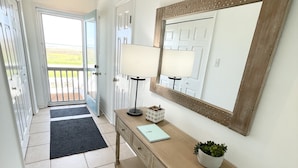 A hallway with a wooden console table, a mirror, and a door leading to a balcony.