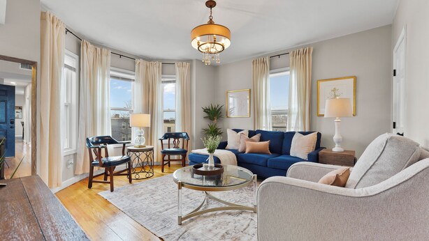 A living room with a blue sofa, a round coffee table, and a chandelier.