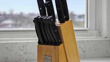 A knife block with multiple knives on a wooden surface near a window.