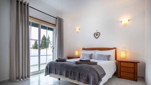 Ein Schlafzimmer mit einem Bett, zwei Nachttischen, einem Vorhangfenster und zwei Wandleuchten.