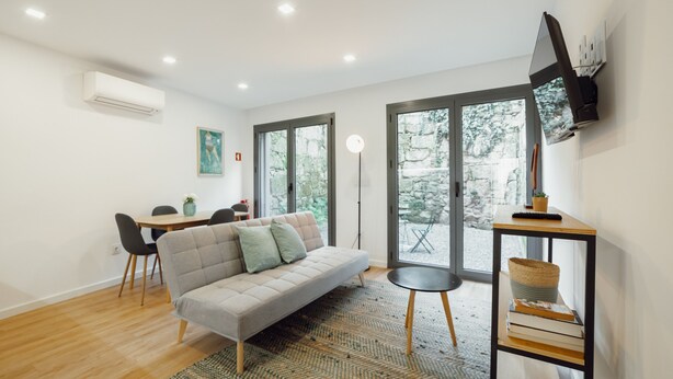 Una sala de estar moderna con un sofá, una mesa de comedor con sillas, una lámpara de pie y una estantería.