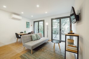 Un salon moderne comprenant un canapé, une table à manger avec des chaises, un lampadaire et une bibliothèque.