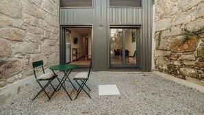 Un edificio de piedra con diseño moderno, que cuenta con un pequeño espacio al aire libre con una mesa y sillas.