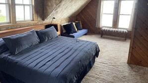 Een slaapkamer met een groot bed, een bankje en een bureau.