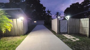 Un sendero que conduce a una zona vallada, con una cerca de madera y un portón de metal.