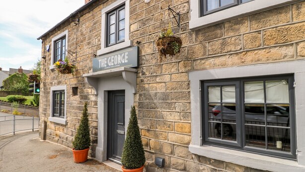 Ein Steinhaus mit einem Schild, auf dem 'The George Country Pub & Dining' steht.
