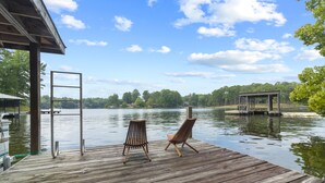 A wooden dock with two chairs facing a calm lake, surrounded by trees and a clear sky. - Lake Hamilton Waterfront Home Dock, Firepit, Sleeps 12 (Hot Springs)