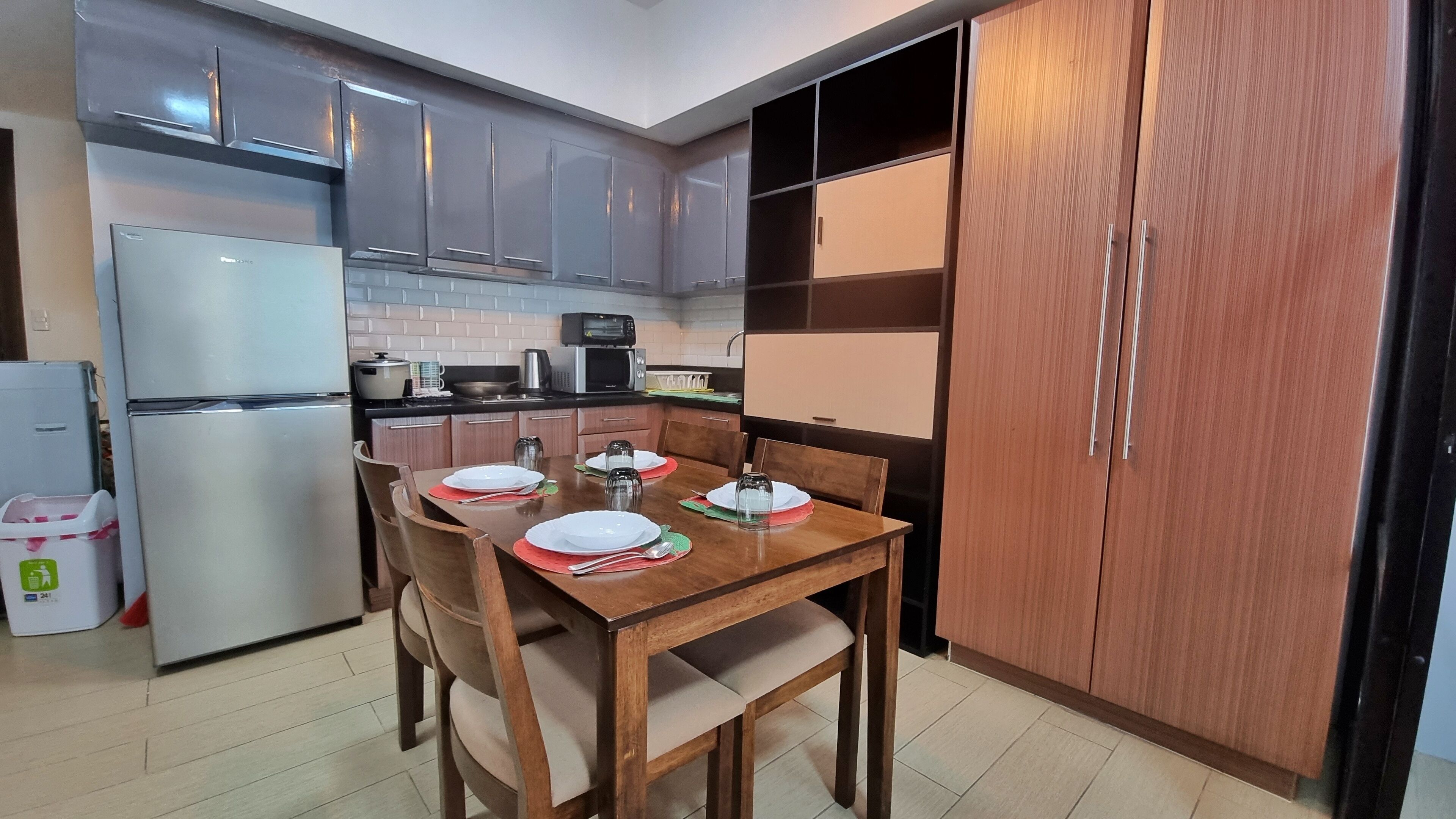 Une cuisine compacte dotée d’appareils électroménagers modernes, une table à manger pour quatre personnes et un grand meuble en bois.