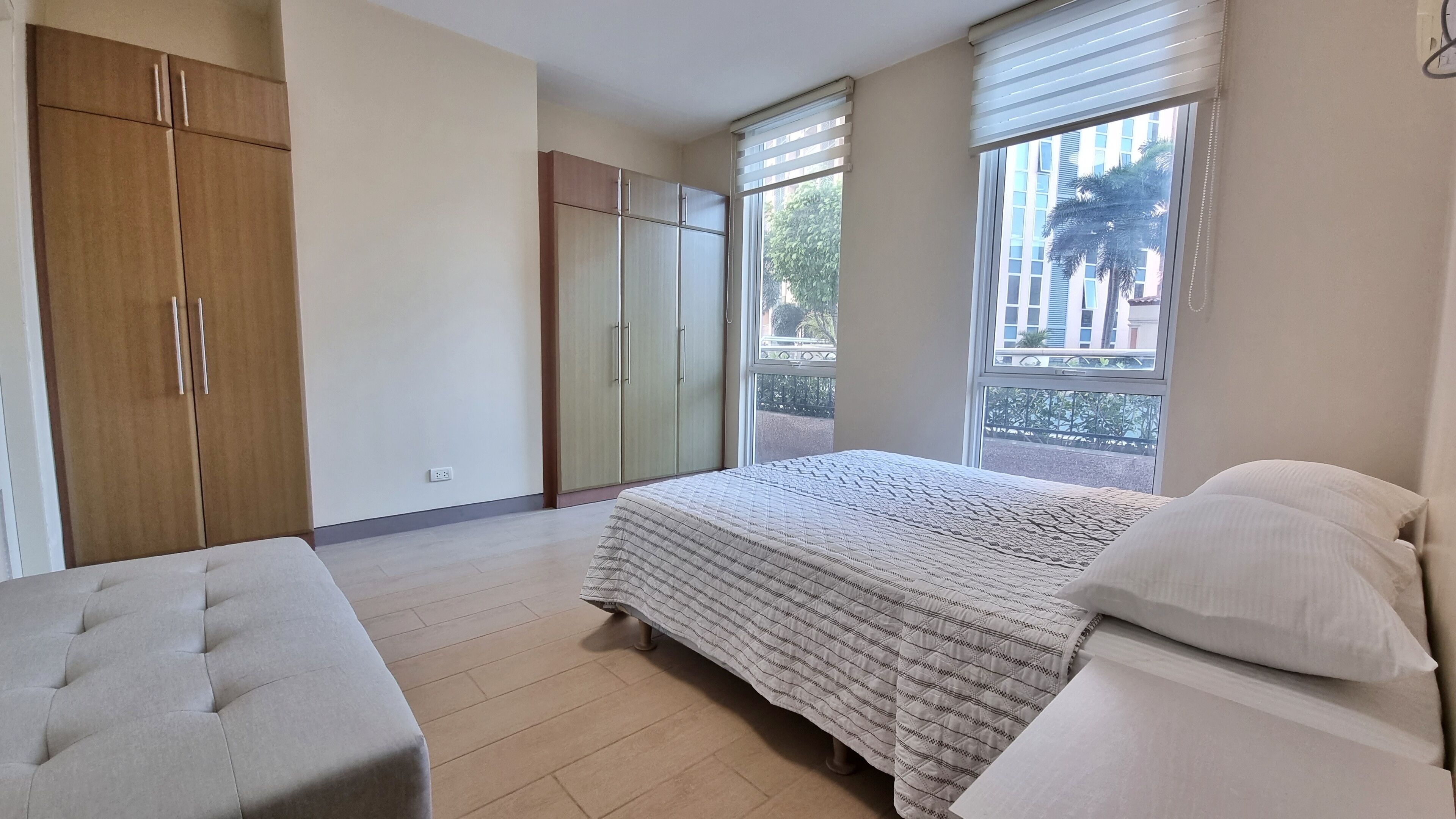 A bedroom with a bed, a bench, and two wardrobes.