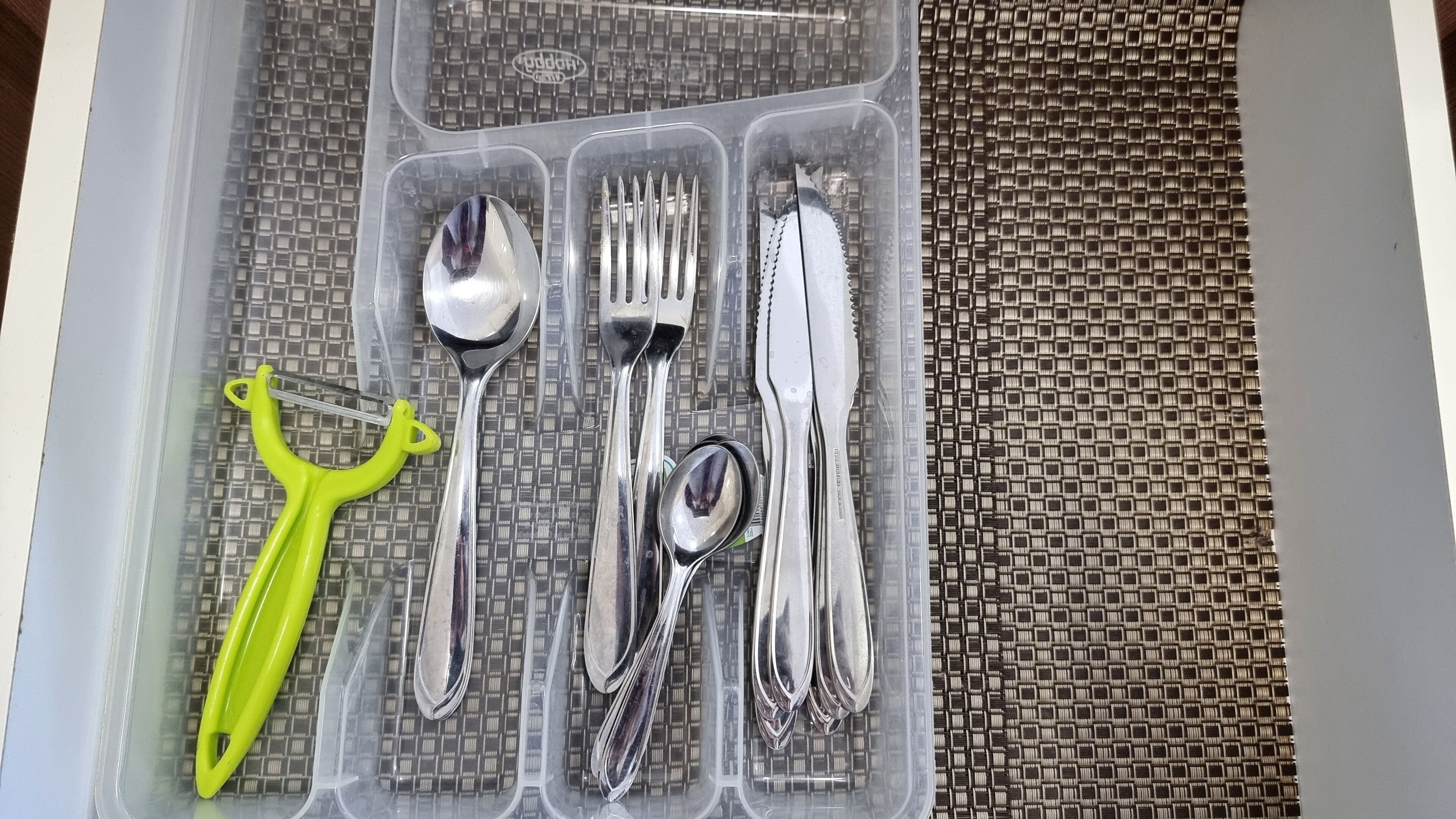 Un recipiente de plástico con cubiertos varios, incluyendo cucharas, tenedores y cuchillos.