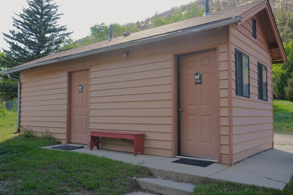 A small, single-story building with two doors and a bench outside. - Cabin 7 at Sportsman's Lodge (Larimer County)