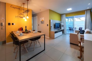 A modern hotel room with a dining area, a sofa, and a TV.
